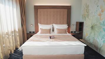 A hotel room with a large bed, a wooden headboard, and a floral wall mural.