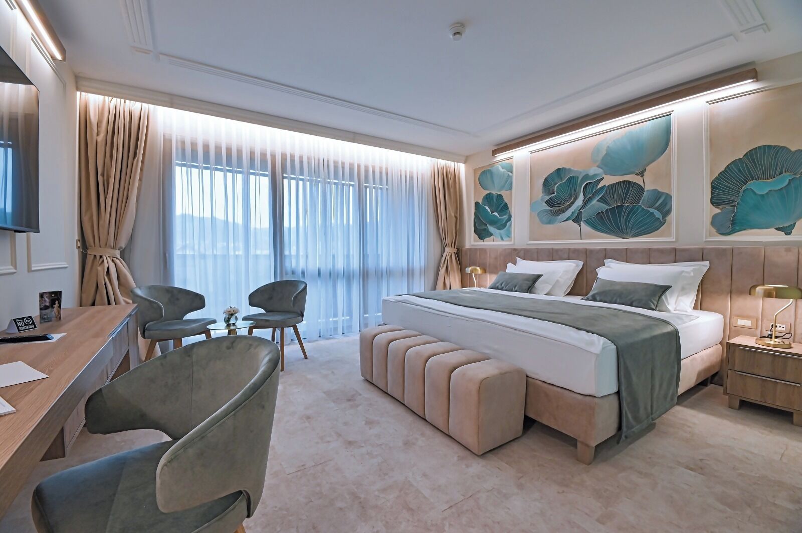 Une chambre d’hôtel moderne avec un grand lit, un bureau, deux chaises et un téléviseur.