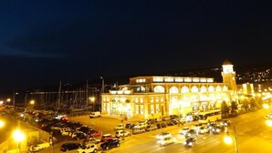 Un grand bâtiment illuminé, doté d’une tour horlogée, entouré d’un parking où sont garées de nombreuses voitures.
