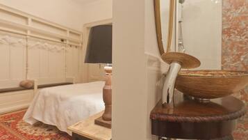 A bedroom with a bed, a nightstand, a lamp, and a large mirror.