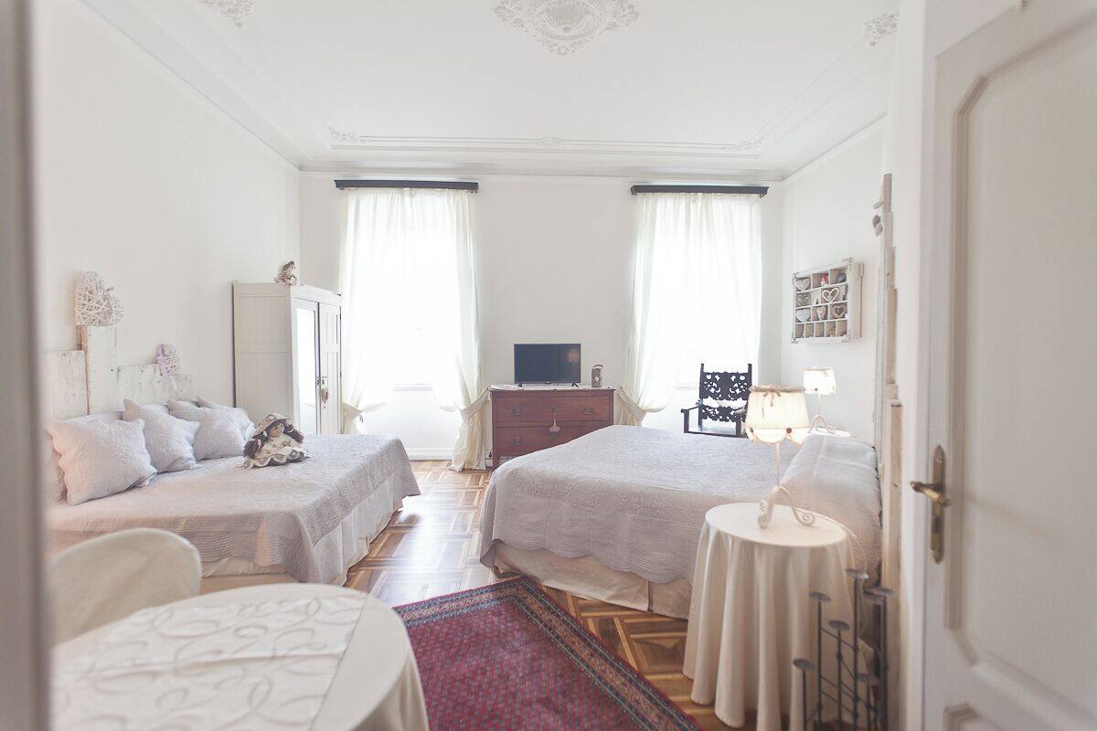 A hotel room with two beds, a dresser, a television, and a small table with a lamp.