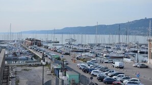 Un port de plaisance où de nombreux bateaux sont amarrés et une rangée de voitures est garée le long du quai.