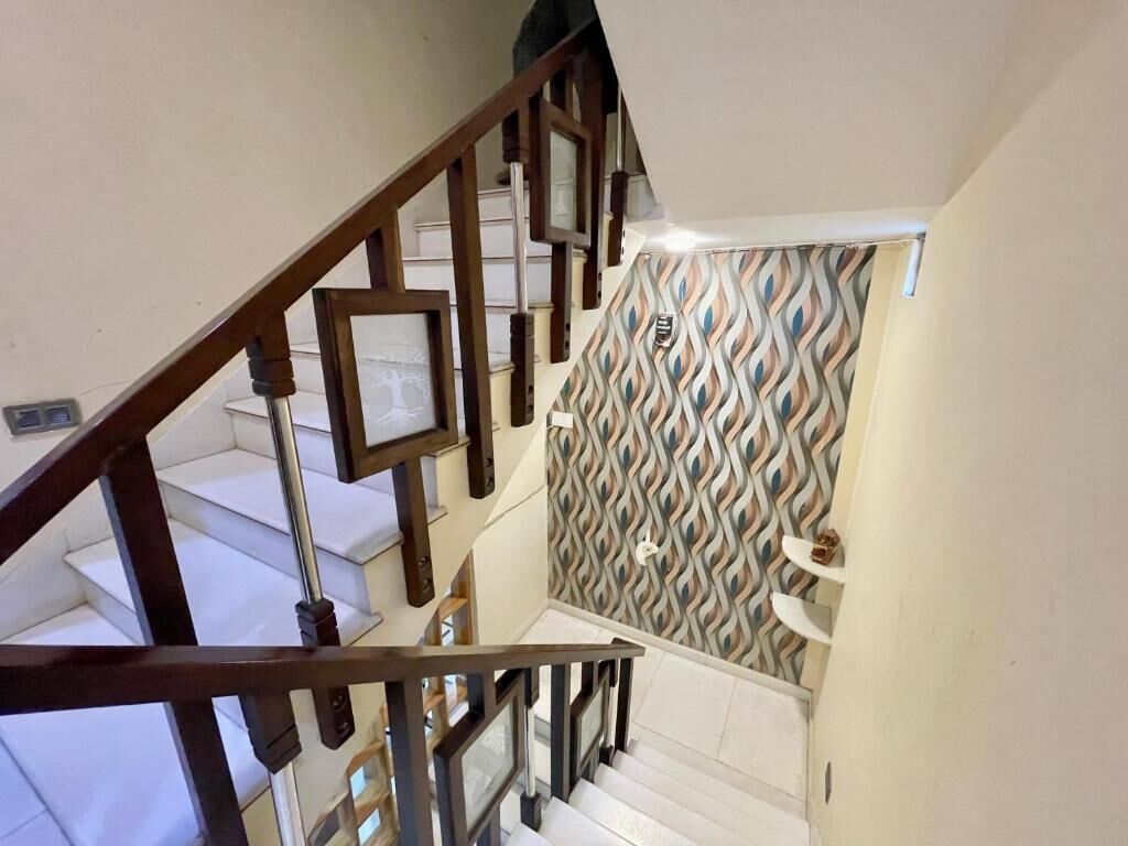 A staircase with wooden railings and patterned wall tiles.