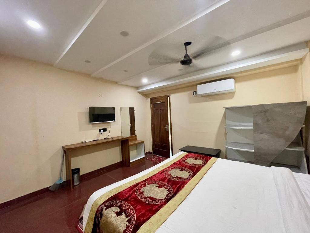 Ein Hotelzimmer mit Bett, Fernseher, Schreibtisch, Deckenventilator und Kleiderschrank.