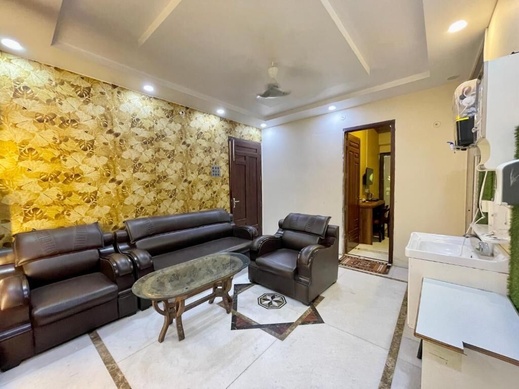 A living room with a sofa, armchair, coffee table, and a decorative wall.