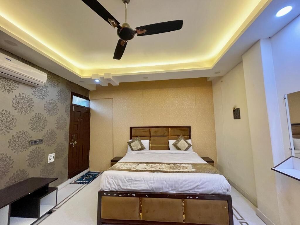 Una camera d'albergo moderna con un letto, ventilatore a soffitto e televisore integrato.