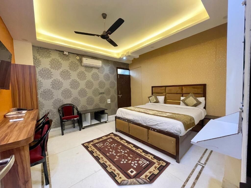 A bedroom with a bed, a desk, a chair, a ceiling fan, and a patterned rug.