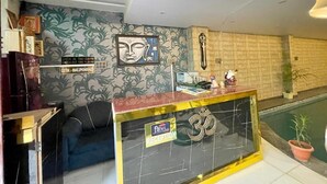Ein Empfangsbereich mit Empfangstresen, einer Couch, einer Wand mit floralem Muster und einem Pool.