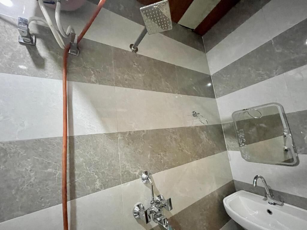 A bathroom with striped tile walls, a shower, a sink, and a mirror.