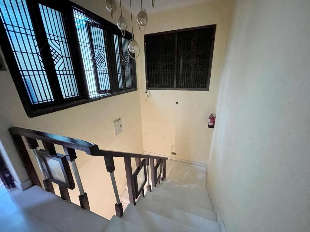 A staircase with a handrail, a window with decorative bars, and a wall-mounted fire extinguisher.