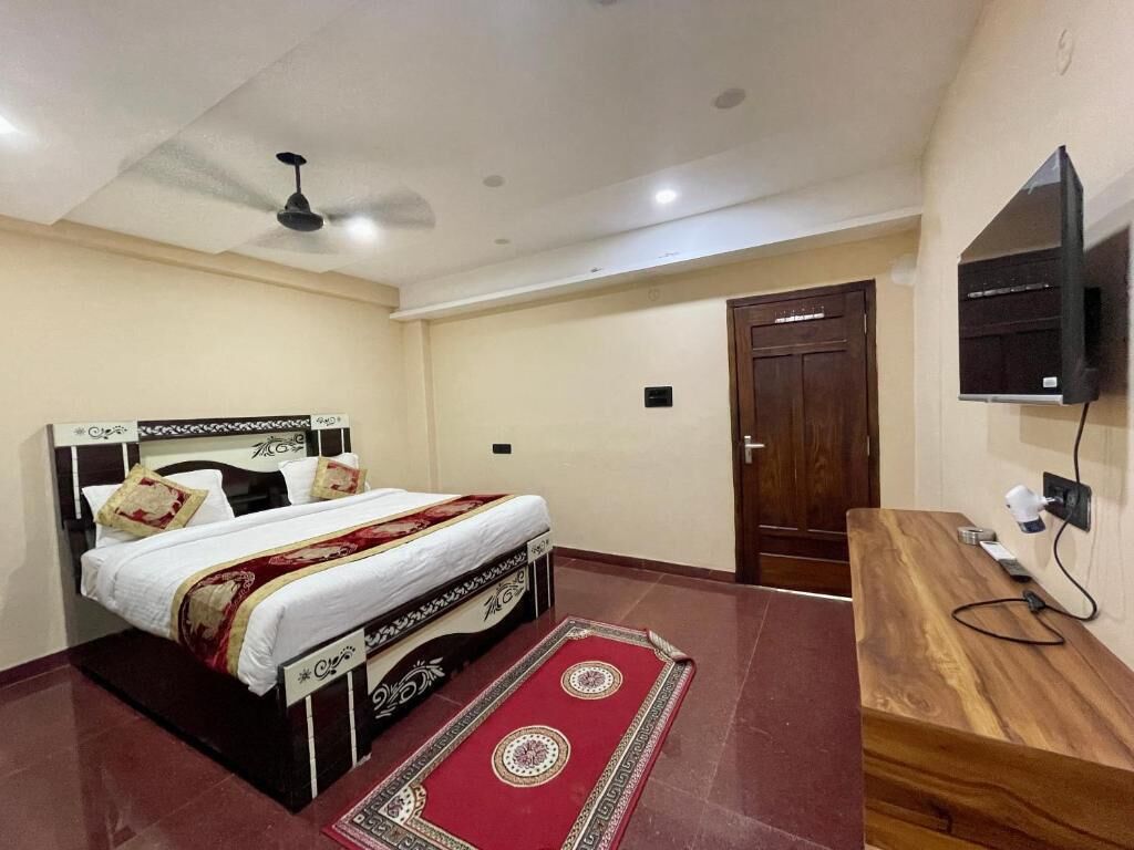 Een slaapkamer met een bed, een houten bureau, een televisie en een deur.