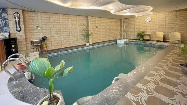 Ein Hallenbad mit modernem Deckenstil, einer Uhr und Sitzbereichen.