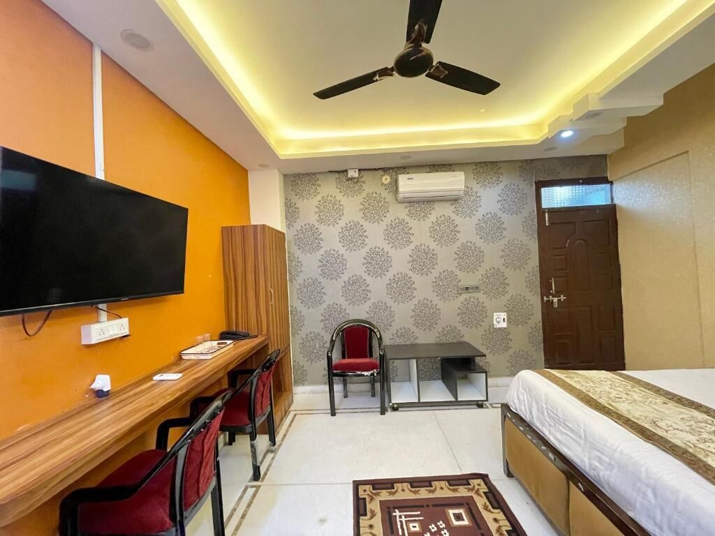 A room with a bed, a desk, a chair, a television, and a ceiling fan.