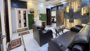 Ein modernes Wohnzimmer mit einer Couch, einem Glastisch und einem Kamin. Eine grüne Akzentwand und ein Marmorkaminumrandung sind ebenfalls vorhanden.