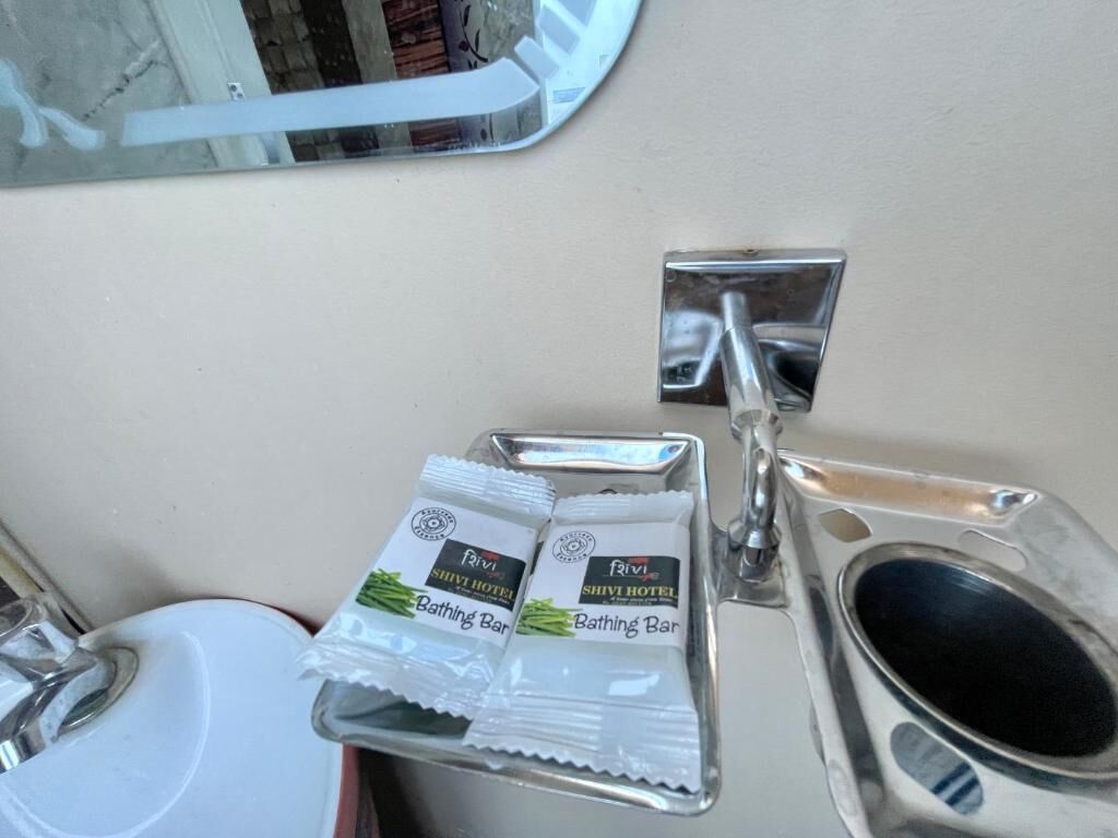 A bathroom with a sink, a mirror, and a tray with two packages labeled "Rivish Hotel Bathing Bar".