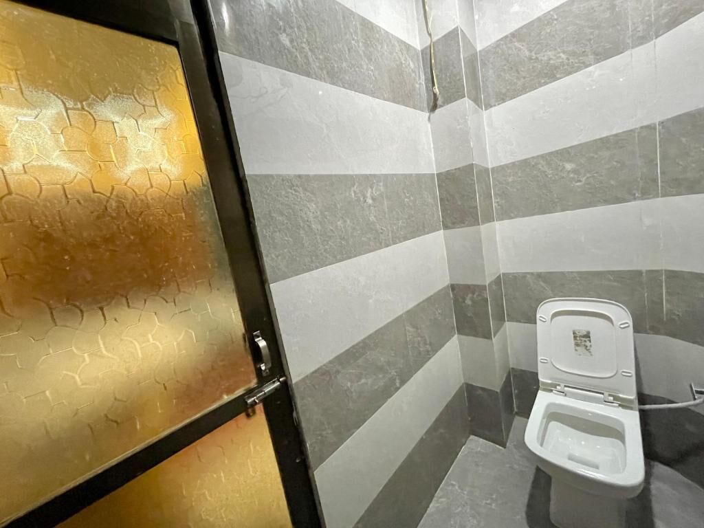 A bathroom with a toilet, tiled walls, and a glass door with a hexagonal pattern.