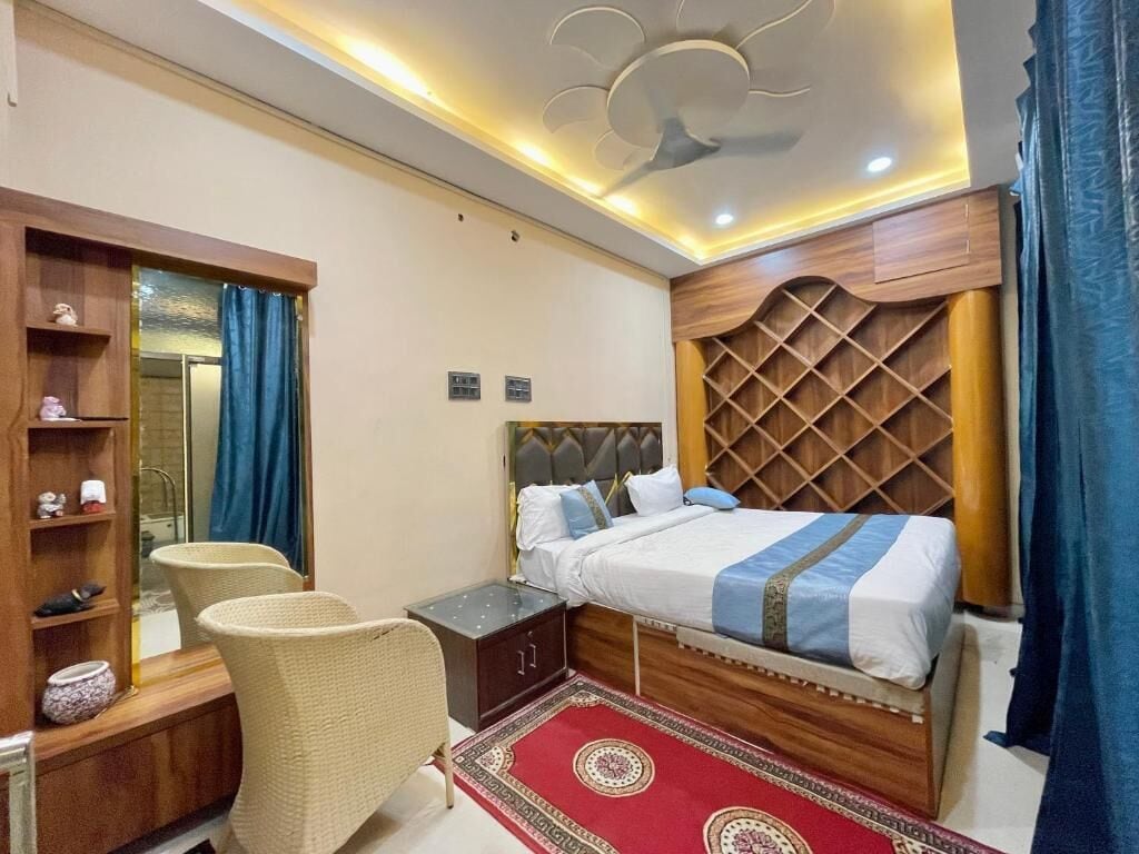 Ein Schlafzimmer mit Bett, Nachttisch, Stuhl und einer Holzregaleinheit.
