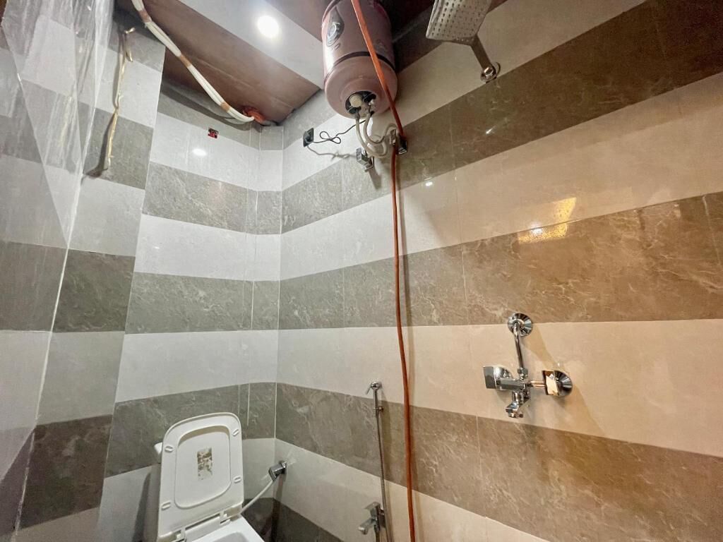 A bathroom with a shower, a toilet, and a tiled wall.