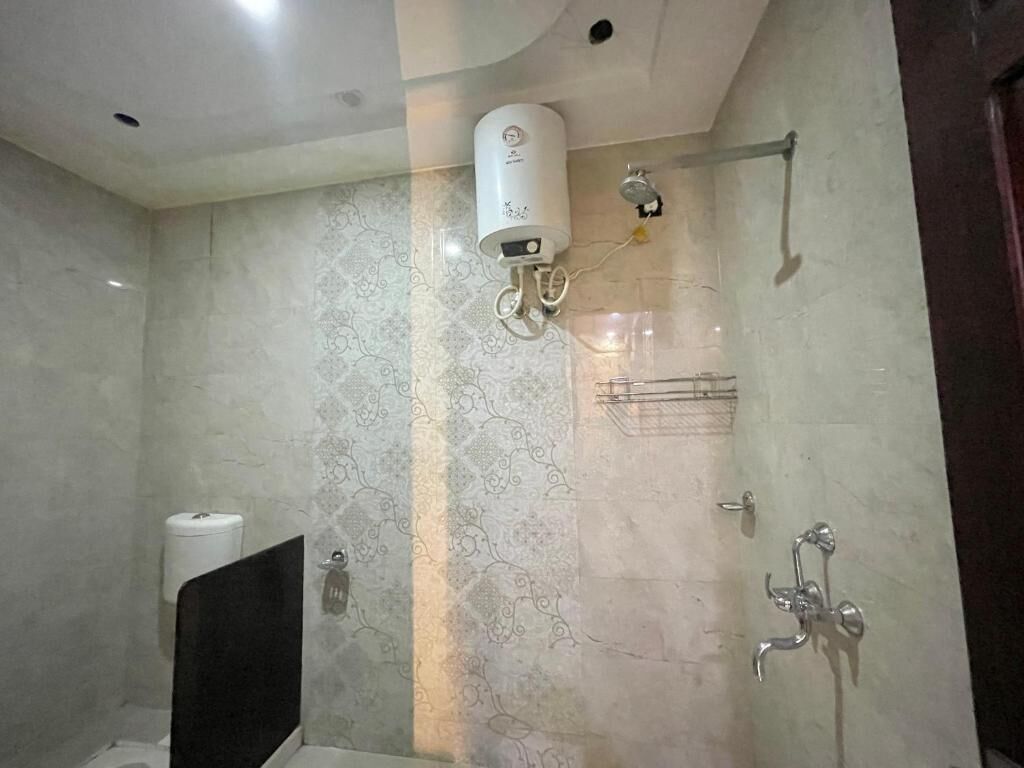 Une salle de bain équipée d’une douche, de toilettes et d’un chauffe-eau fixé au mur.