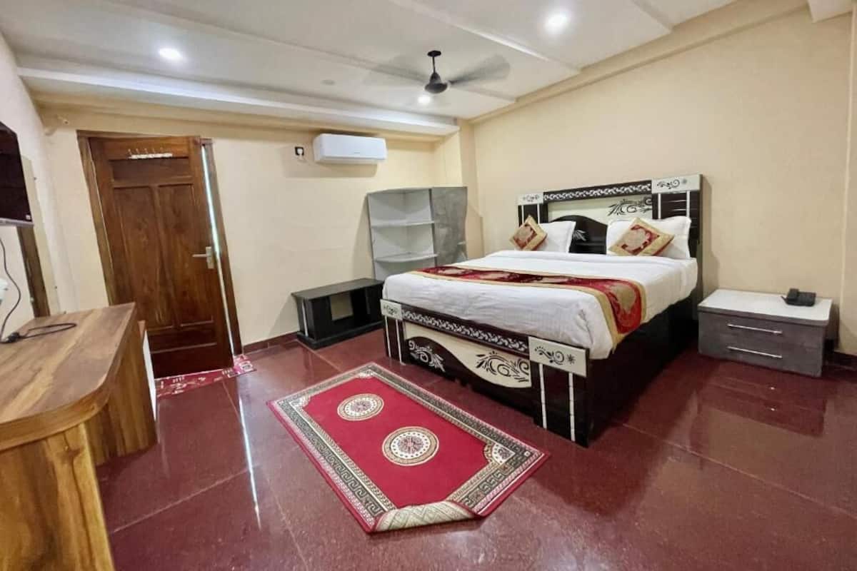 Una camera da letto con un letto, comodini, una scrivania e un tappeto rosso decorato.