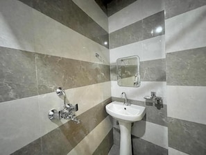 A bathroom with striped marble walls, a white sink, and a shower. - Hotel Shivee - Varanasi (Varanasi)