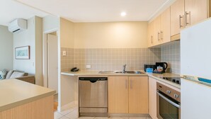 Una cocina compacta con gabinetes de madera, lavavajillas, estufa y cafetera.