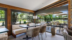 A modern outdoor patio with a seating area, tables, and umbrellas. - Regnum Banya Thermal Hotel (Razlog)