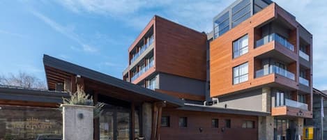 Un immeuble moderne à plusieurs étages, dont la façade est un mélange de briques et de verre, doté de grandes fenêtres et d’un espace d’entrée abrité.
