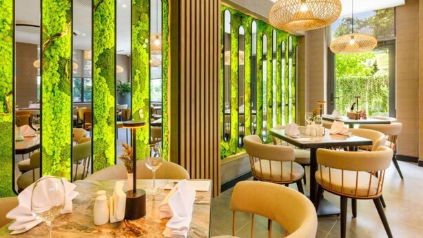 A restaurant with green foliage walls, wooden panels, and modern furniture. - Regnum Banya Thermal Hotel (Razlog)