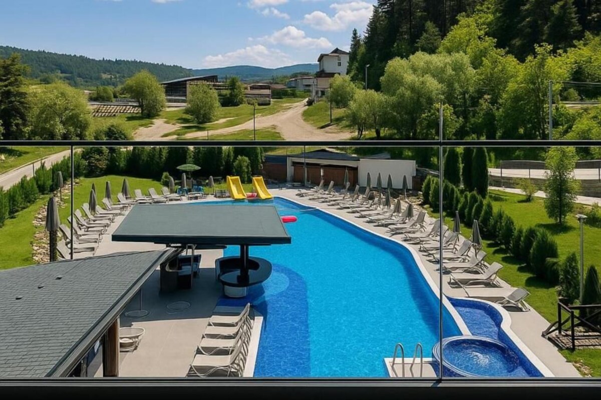 A swimming pool with a slide, lounge chairs, and a table with umbrellas.