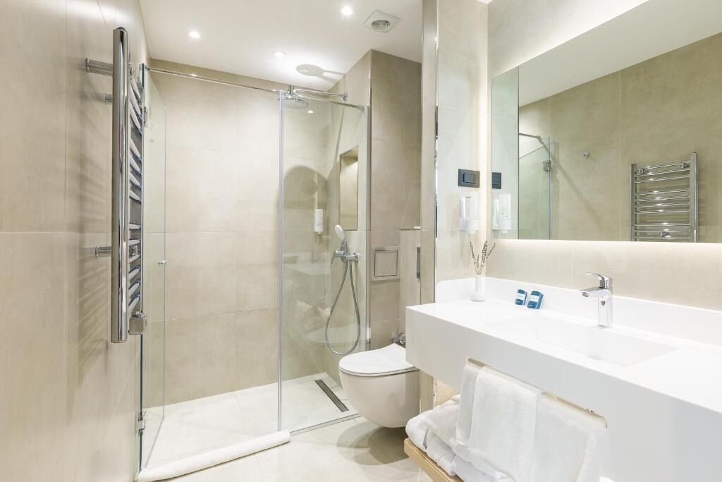 A modern bathroom with a glass-enclosed shower, a white sink, and a large mirror.