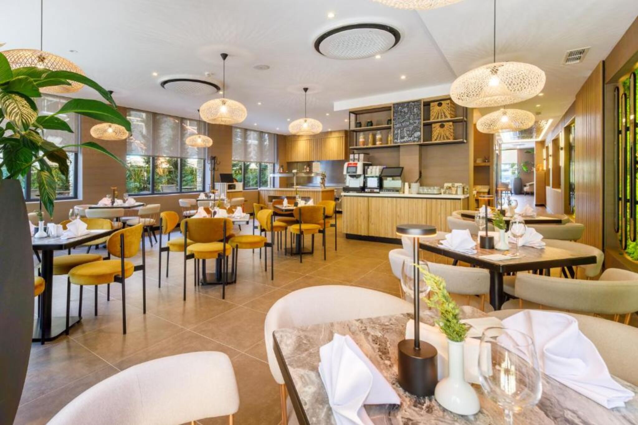 A modern restaurant with yellow chairs, marble tables, and pendant lighting.