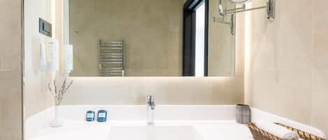 Un baño moderno con un lavabo blanco, un espejo y un cesto para toallas.