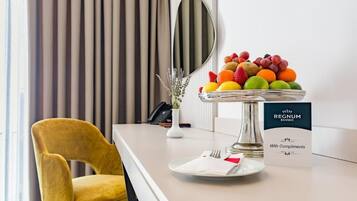 A hotel reception area with a fruit bowl, a chair, a mirror, and a sign reading "REGNUM BANSKO With Compliments".