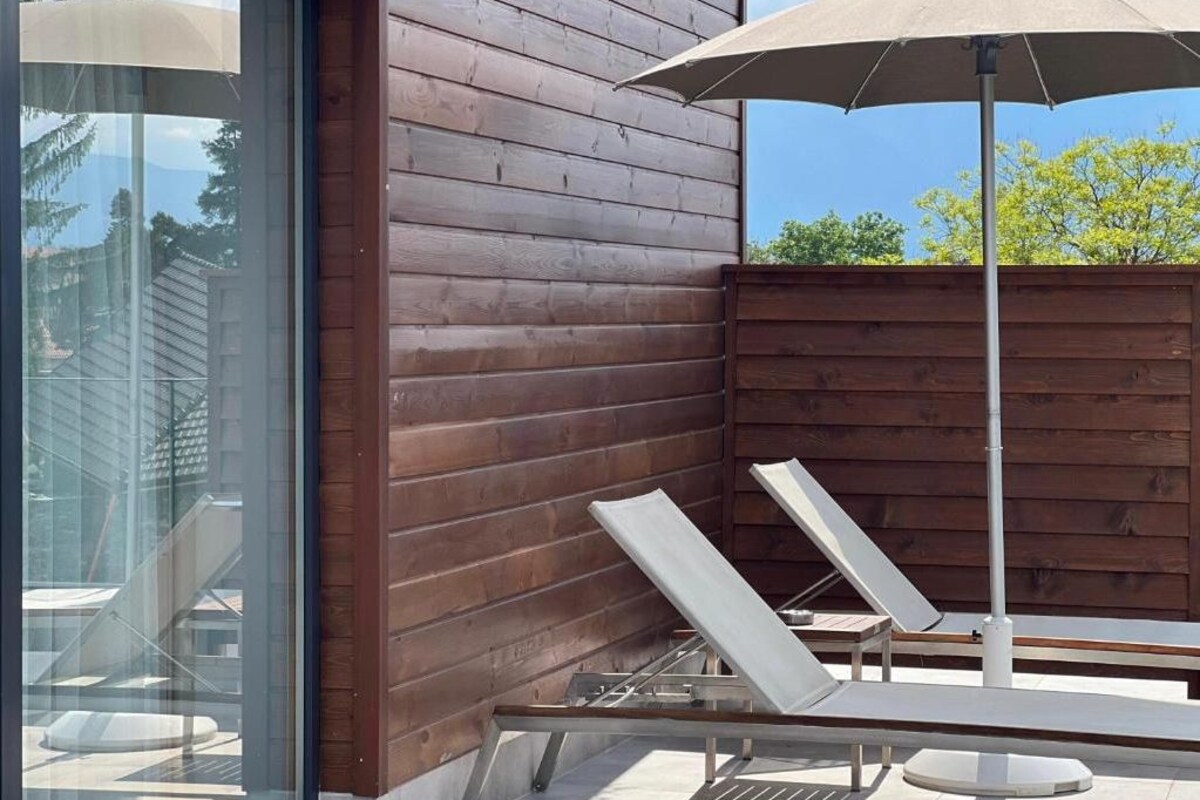 A wooden deck with two lounge chairs and a large umbrella.