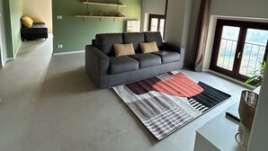 Un salon moderne avec un canapé gris, un tapis à motifs et un mur d’accent vert.