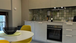 Une cuisine moderne avec un plan de travail blanc, un four encastré et un coin repas avec des chaises jaunes.