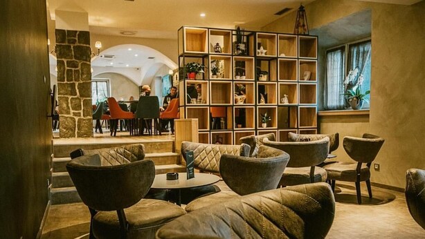 A lobby with leather armchairs, a wooden bookshelf, and a stone pillar.