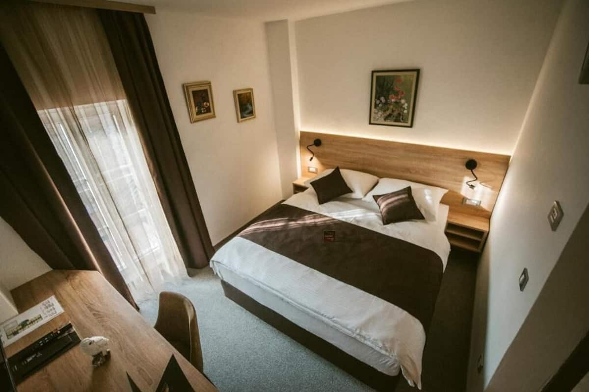 Una habitación de hotel con cama, mesitas de noche, escritorio y silla.