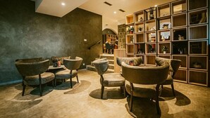 A cozy lounge area with multiple armchairs and a bookshelf filled with decorative items.