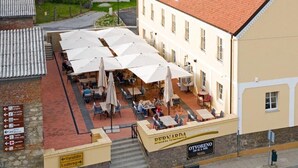 An outdoor café with multiple tables and umbrellas, a sign for 'Bernarda', and a sign for 'Otvoreno'.