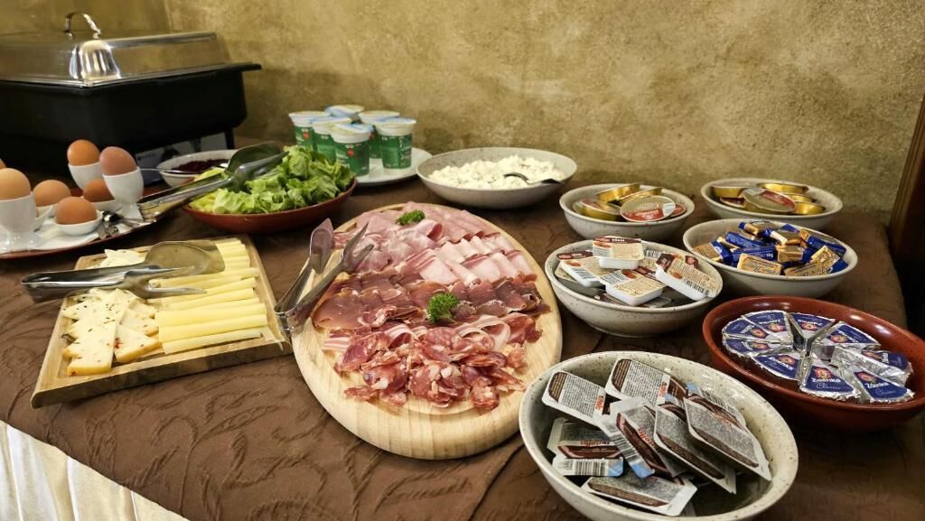 A buffet table with various food items including meats, cheeses, and condiments.