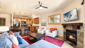 A living room with a fireplace, a sofa, a coffee table, and a television mounted on the wall. - Luxury Townhome, Private Balcony, Great Location, 3 Bedrooms, Hot Tub! (Park City)