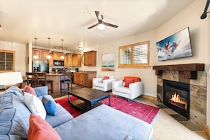 A living room with a fireplace, a sofa, a coffee table, and a television mounted on the wall. - Luxury Townhome, Private Balcony, Great Location, 3 Bedrooms, Hot Tub! (Park City)