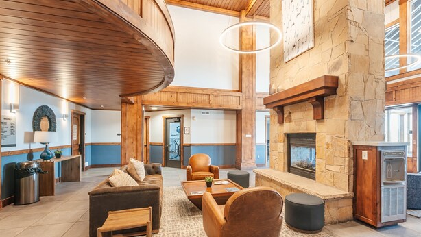 Eine geräumige Lobby mit Kamin aus Stein, Holzboden und Wasserspender.