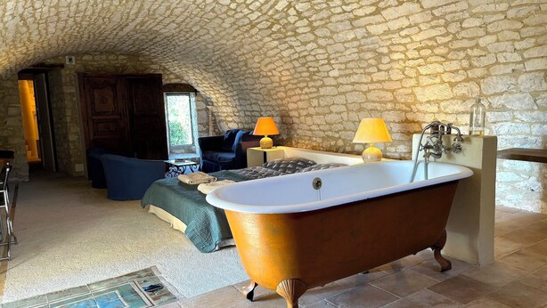 Una habitación con techo de piedra, una bañera, un sofá y un ventanal.