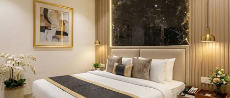 A modern bedroom with a large bed, bedside tables, a framed artwork, and a marble wall.