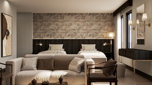A hotel room with a stone wall, two beds, a sofa, a chair, and a bedside table. - Büyük Mardin Otel (Mardin)