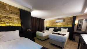 A hotel room with two beds, a wardrobe, a mirror, and a stone wall. - Büyük Mardin Otel (Mardin)