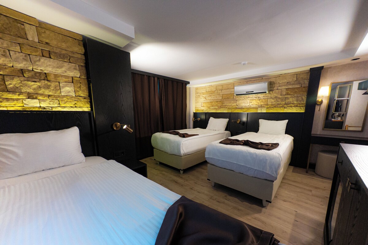 Una habitación de hotel con dos camas, un armario, un espejo y una pared de piedra.